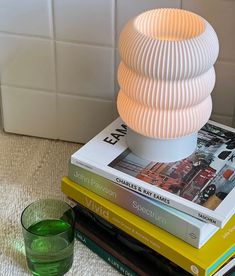 a stack of books sitting on top of each other next to a green glass cup