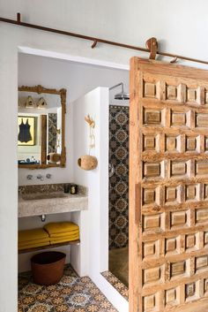 an open door in a bathroom next to a sink and shower with decorative tile on the floor