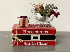 two books stacked on top of each other with christmas decorations in the middle one has a sleigh and presents tied to it