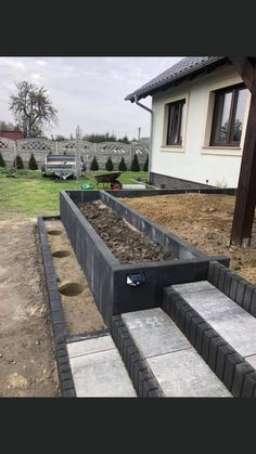 an outdoor garden is being built in front of a house with steps leading up to it