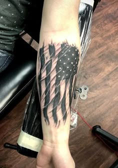 a person with a tattoo on their arm holding an american flag