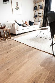 a living room filled with furniture and a white rug on top of a hard wood floor