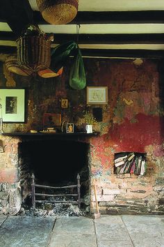 an old fireplace in a stone room with pictures on the wall and hanging baskets above it