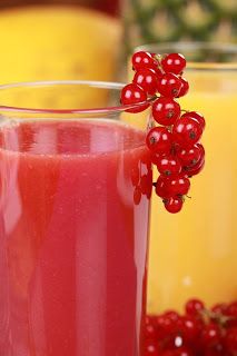 a glass filled with liquid next to two glasses full of juice and some berries on the side