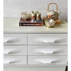 a white dresser topped with two tea pots and cups