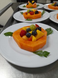 four plates with fruit arranged on them sitting on a counter top, ready to be eaten