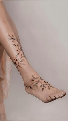 a woman's foot with flowers and leaves tattooed on the side of her leg