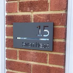 a house number sign mounted to the side of a brick building that reads 15 swan mead