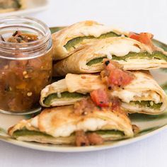 several quesadillas on a plate with a jar of salsa