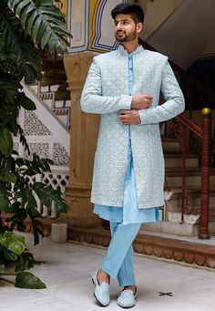 a man standing in front of some stairs wearing a light blue sherve with white flowers on it