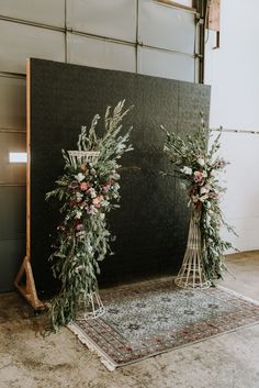 two tall floral arrangements on display in front of a black backdrop with white and pink flowers