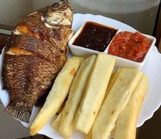 a white plate topped with fish, fries and ketchup on top of a table