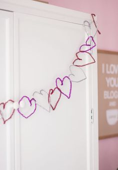 some pink hearts are hanging on the side of a white door with i love you sign