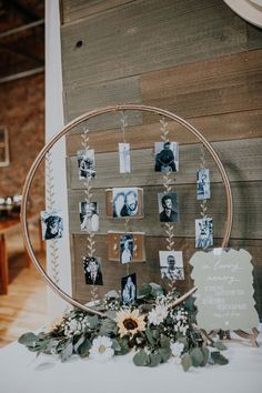 a table topped with pictures and greenery next to a wall mounted on a wooden board