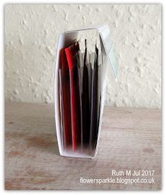 a stack of red and white papers sitting inside of a clear container on top of a wooden table