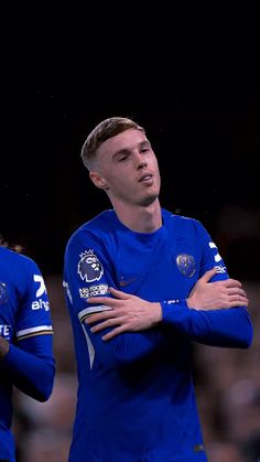 two soccer players standing next to each other with their arms crossed in front of them