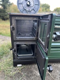 an open oven sitting on the ground next to a green box with its door open