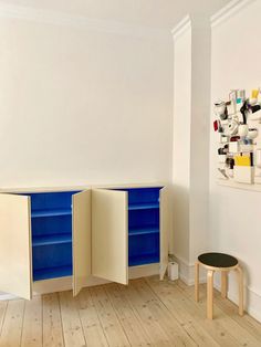 an empty room with two blue and white cabinets in front of a wall mounted art piece