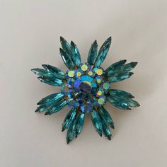 a brooch with blue and yellow stones on it's center, sitting on a white surface