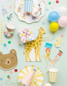 a table topped with lots of party supplies and balloons on top of a blue surface