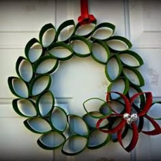 a christmas wreath made out of rolled up paper and ribbon hanging on the front door