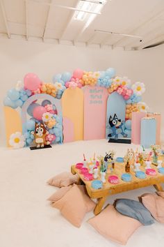 a birthday party setup with balloons, cake and other decorations on the floor in an empty room