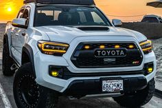 a white toyota truck parked in front of the ocean