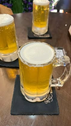 two mugs of beer sitting on top of a wooden table