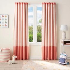 a child's room with pink curtains and toys on the floor in front of a window