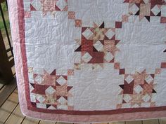 a pink and white quilt on a wooden deck