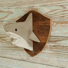 a wooden carving of a shark on a wood planked wall, with the mouth open