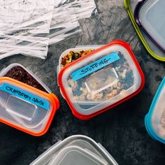 four plastic containers filled with food sitting on top of a table