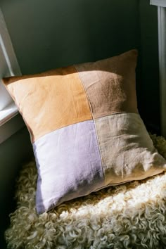 a pillow sitting on top of a fluffy rug next to a window