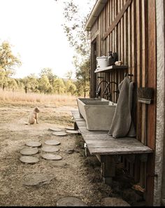 there is a dog sitting on the porch next to an old bathtub and sink