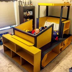 a child's bed made out of cardboard with shelves underneath it and a doll in the middle