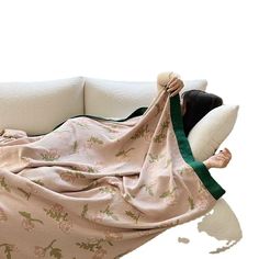 a woman laying on top of a couch covered in a blanket