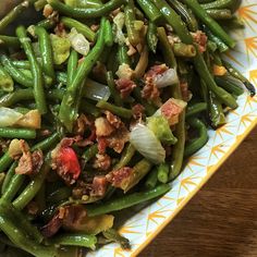 green beans with bacon and onions on a yellow and white plate