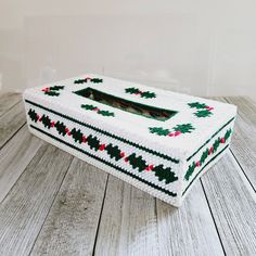 a knitted box sitting on top of a wooden floor next to a white wall