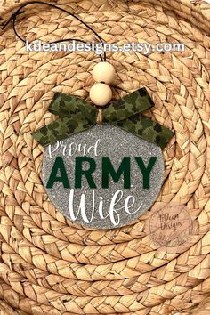 an army wife ornament hanging on a woven basket with a green ribbon around it