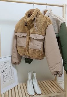 a coat hanging on a rack next to some shoes and a drawing in a frame