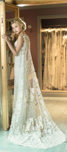 a woman standing in front of a mirror wearing a white dress and holding a veil