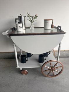 a coffee cart with two cups on it and some other items sitting on top of it