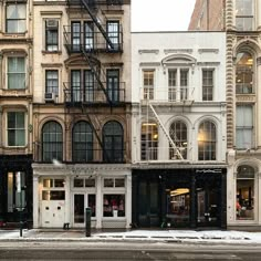 an empty street in front of some buildings with snow on the ground and people walking by