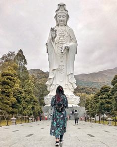 a woman standing in front of a large statue