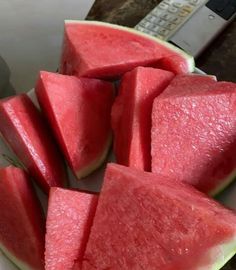 slices of watermelon on a plate with a remote control in the back ground