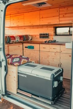 the inside of a van with an open door and storage compartment on the side, filled with items