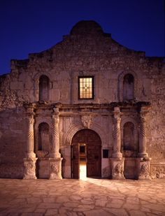 the entrance to an old stone building at night