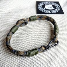 a close up of a bracelet on a bed with a badge in the back ground