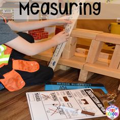 a young boy is sitting on the floor with construction toys and measuring tape to measure his height