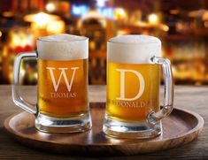 two beer mugs sitting on top of a wooden tray